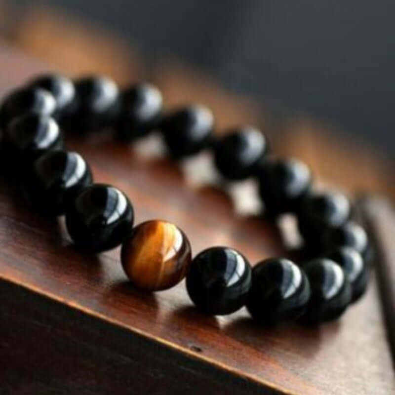 Natural Black Onyx Bracelet with Tiger Eyes Stone on wooden surface.