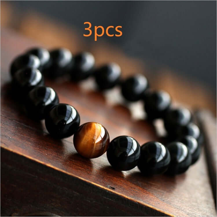 Natural Black Onyx and Tiger Eye Beaded Energy Bracelet on wooden surface.