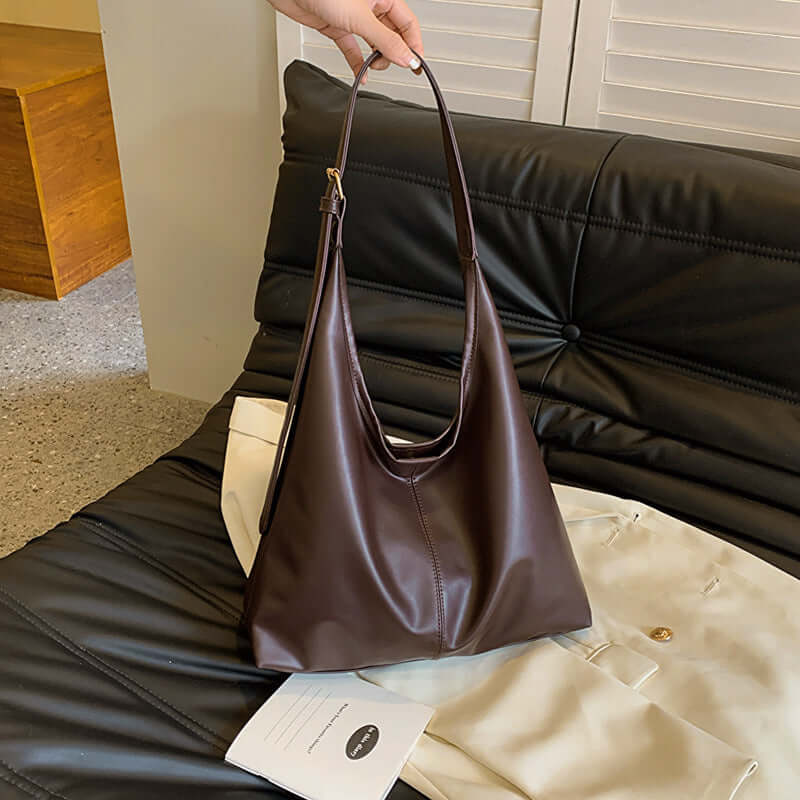 Large capacity commuter tote women's white ditch bag on black leather sofa.