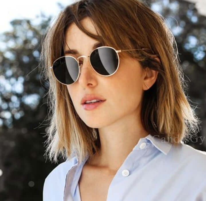 Women wearing round frame retro sunglasses with gold metal frame and grey lenses.