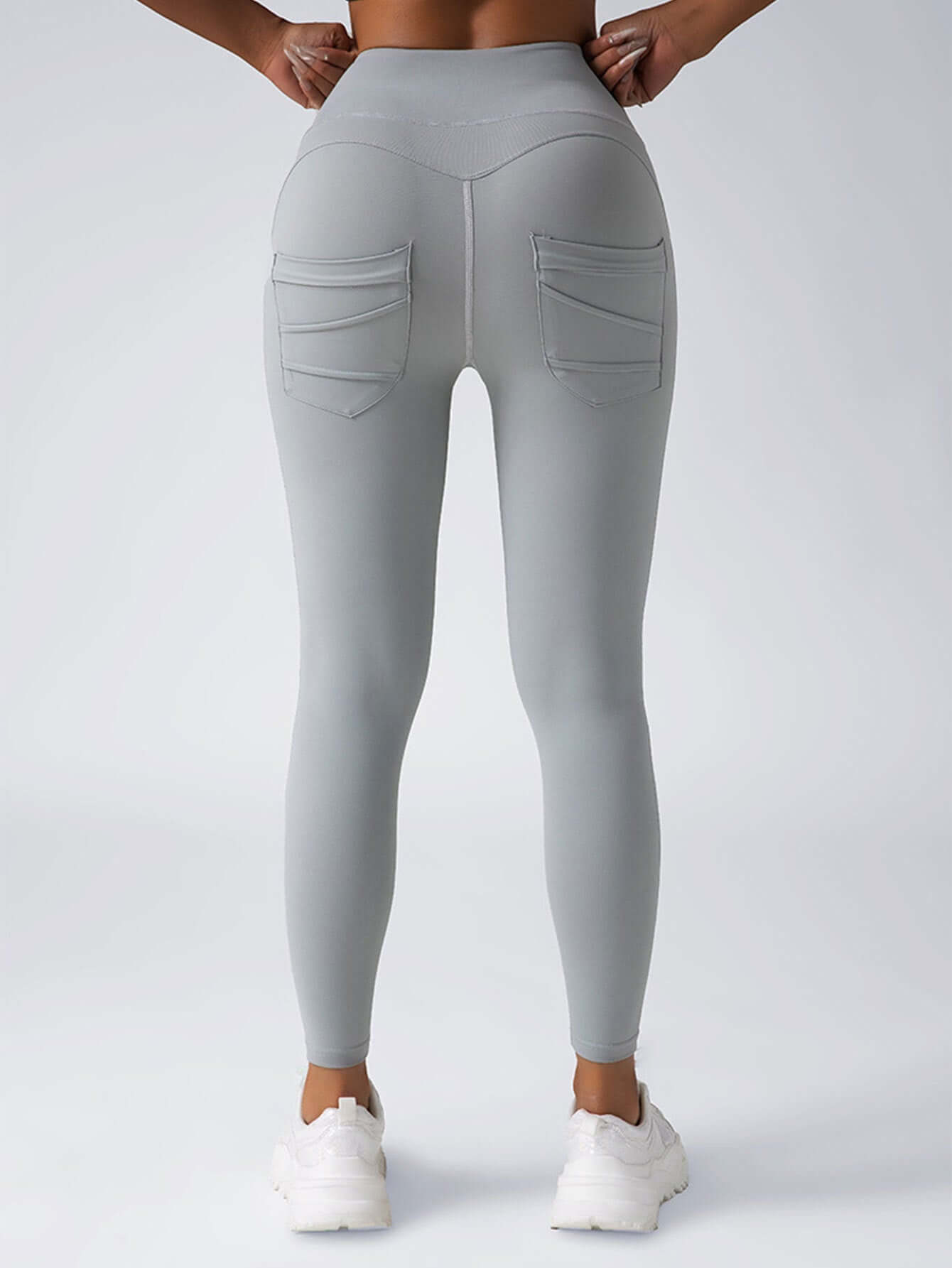 Back view of women's high-waisted gray yoga leggings with pockets, perfect for workouts and daily wear.