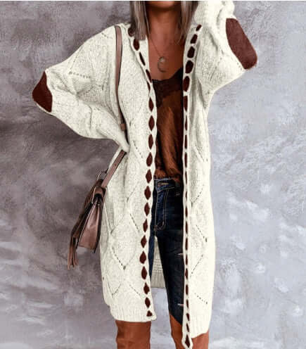 Long cream knit cardigan with brown accents worn over jeans and a top.