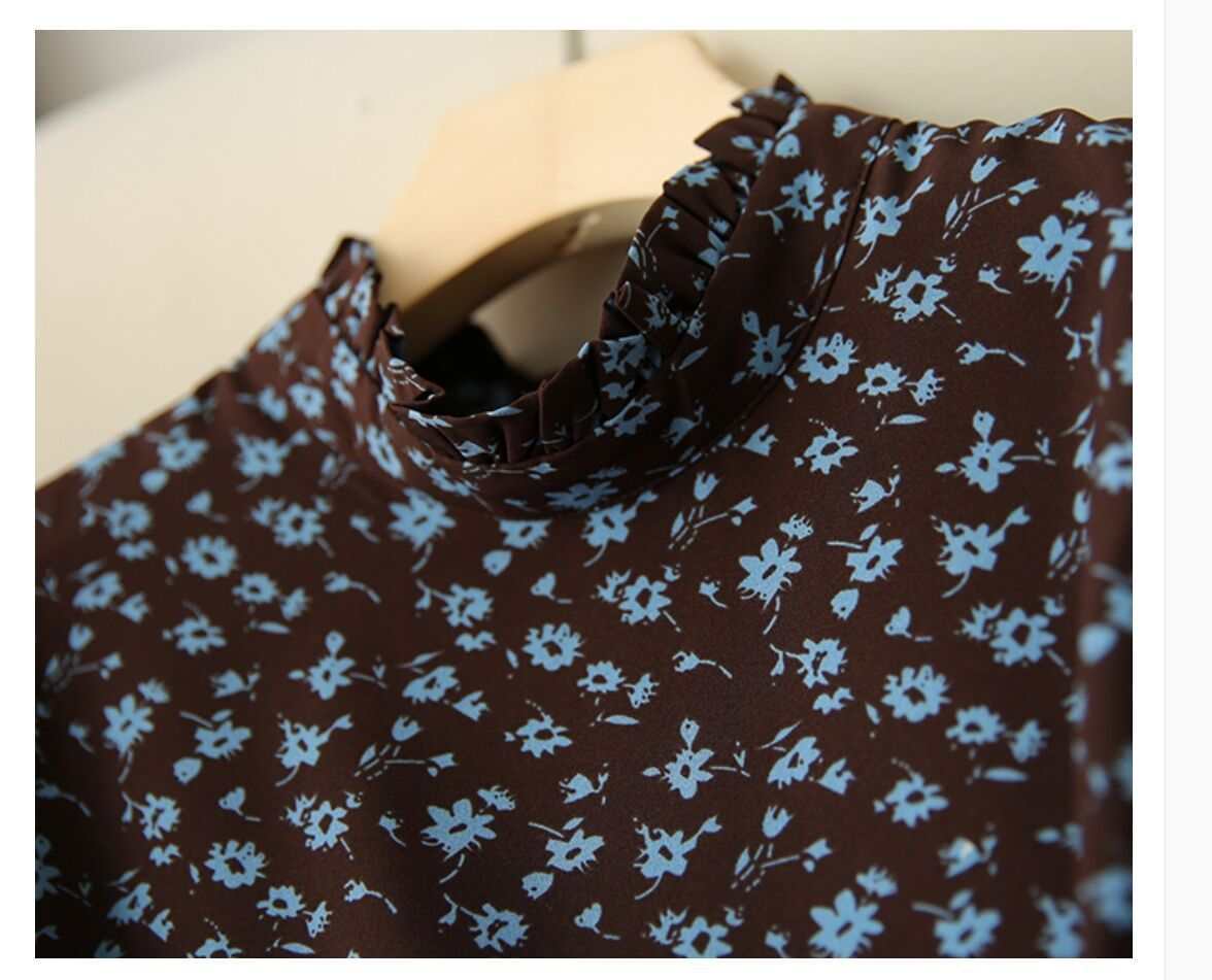 Close-up of a brown dress with blue floral print and ruffled collar detail.