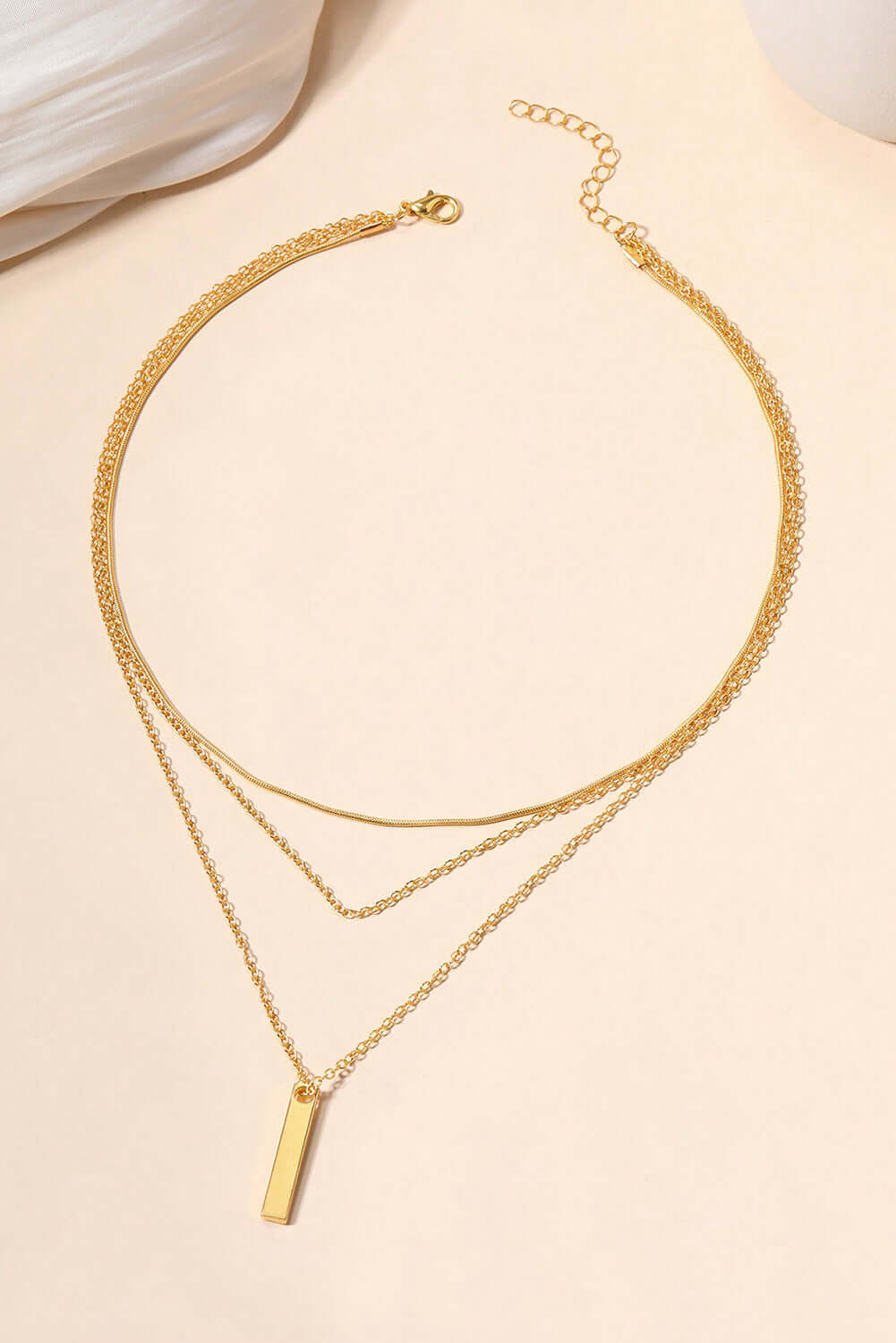 Layered adjustable gold chain necklace featuring a chic gold bar pendant, perfect for versatile styling.