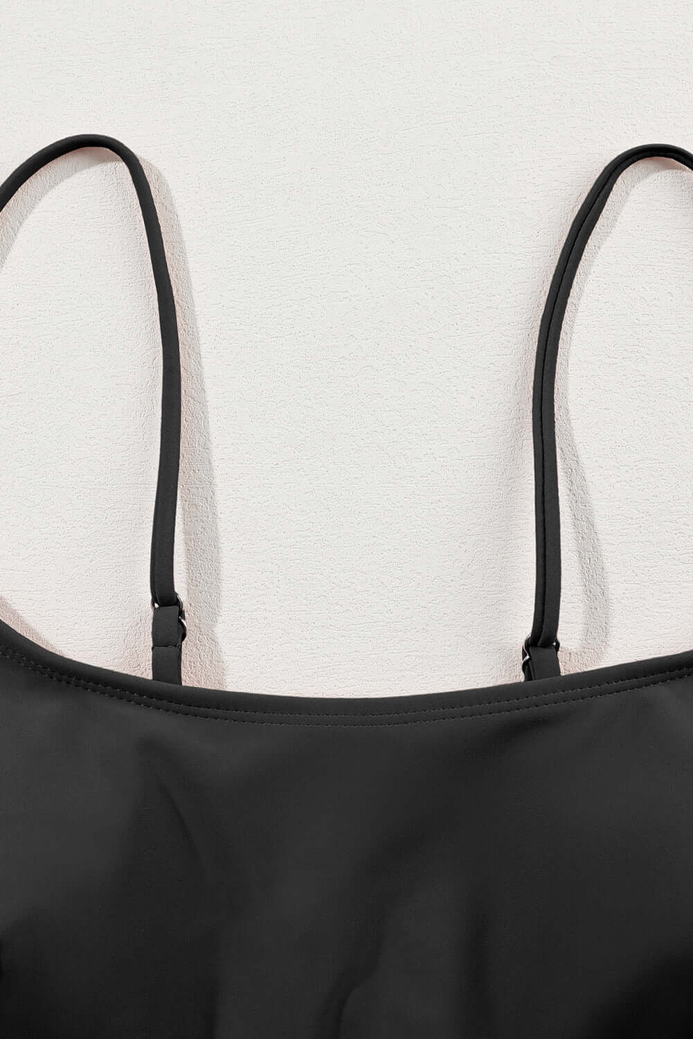 Close-up of spaghetti straps on a black bikini top, showcasing sleek material and high-quality design.