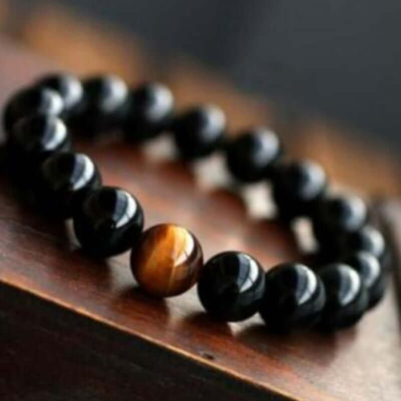 Natural black onyx bracelet with tiger eyes stone on a wooden surface.