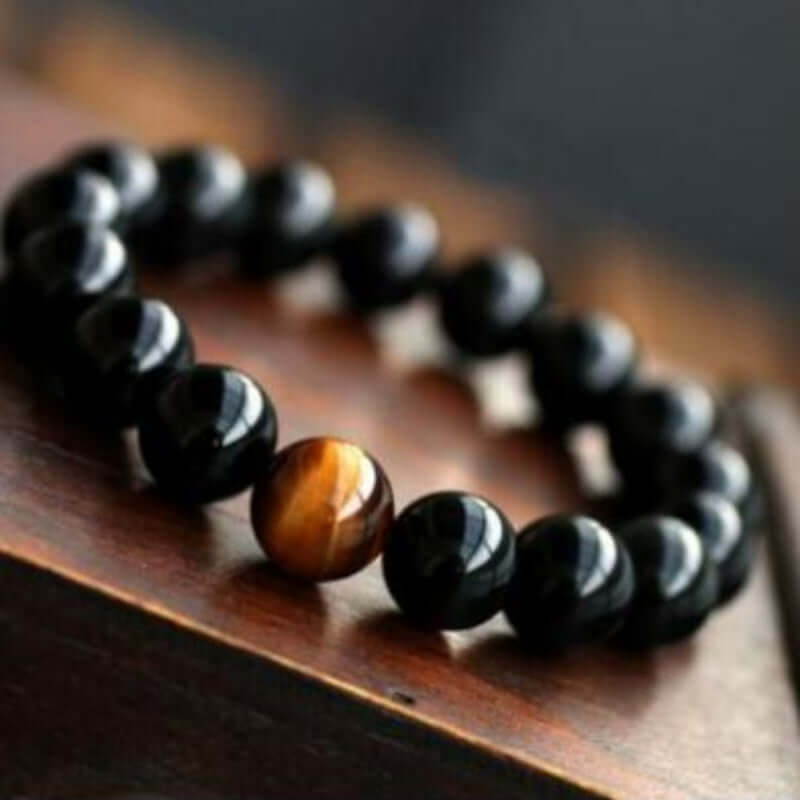 Natural Black Onyx and Tiger Eye Stone Energy Bracelet on wooden surface.