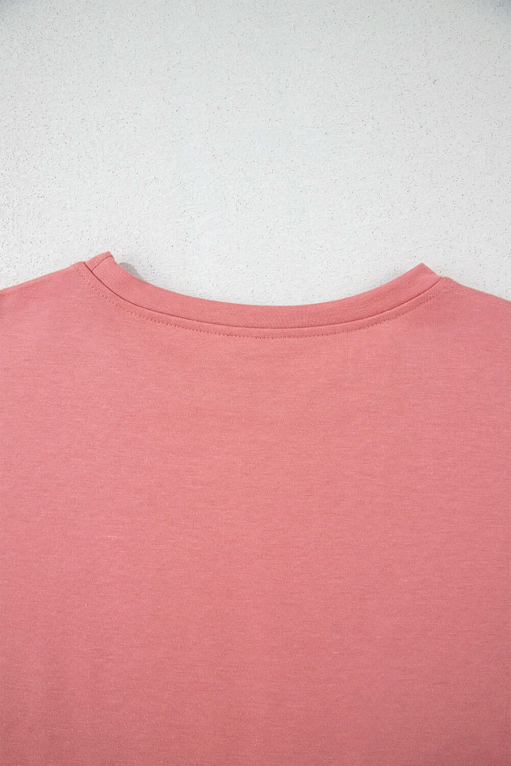 Back view of a pink cropped tee, showcasing the soft fabric and simple design, perfect for casual styles.