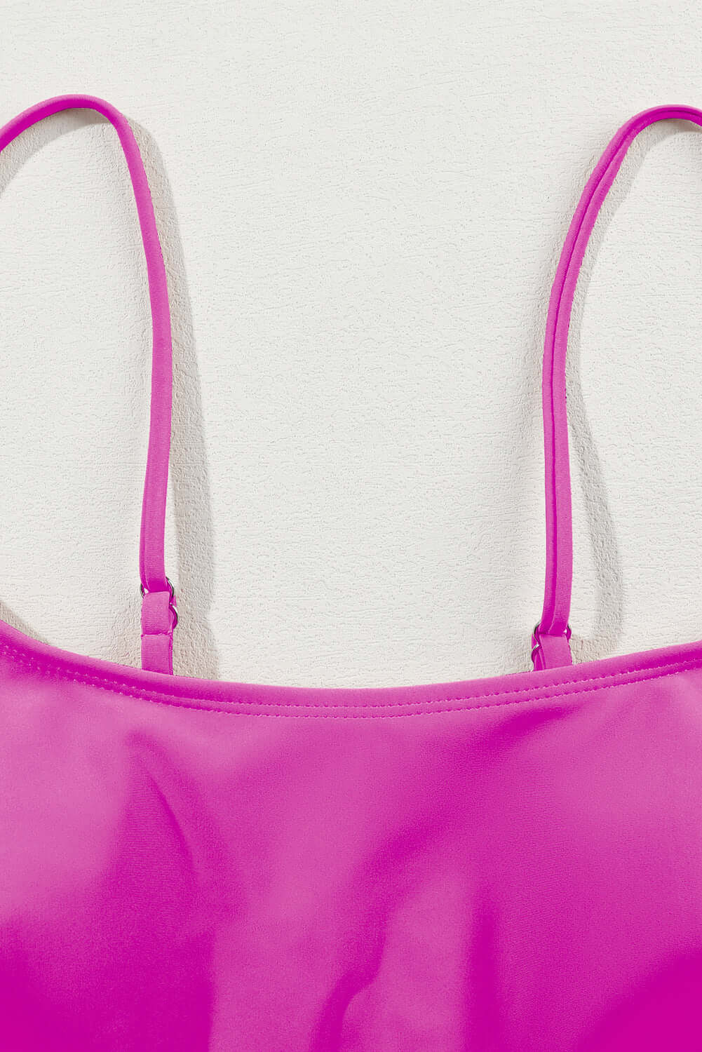 Close-up of pink spaghetti strap bikini top showcasing adjustable straps and smooth fabric.