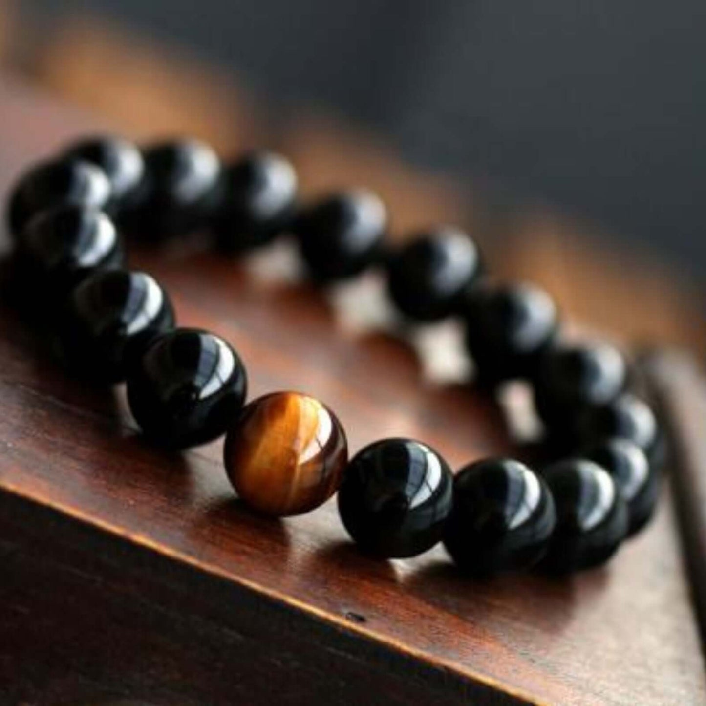 Natural Black Onyx and Tiger Eyes Stone Energy Bracelet on a wooden surface.