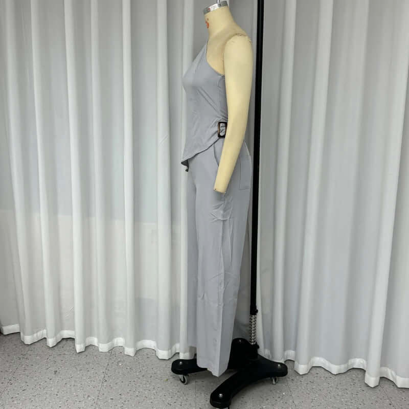 Gray sleeveless top with diagonal collar and high-waist slim pants set on mannequin.