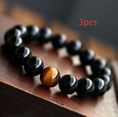 Natural black onyx and tiger eye stone energy bracelet on wooden surface.