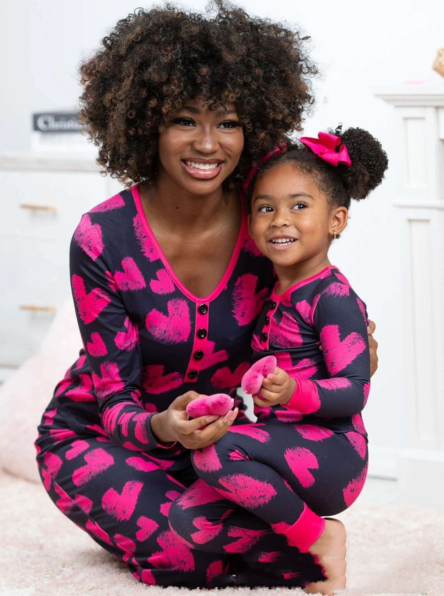 Mother and daughter in matching heart-print pajamas, perfect for Valentine's Day, showcasing comfort and style.