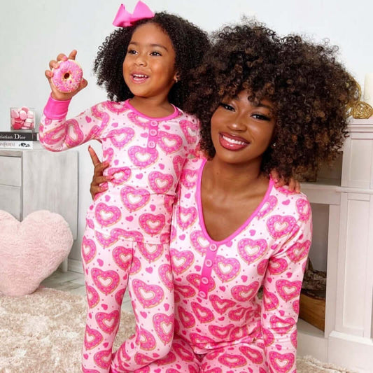 Mother and daughter in matching heart-patterned pajamas, celebrating Valentine's Day with a pink theme.