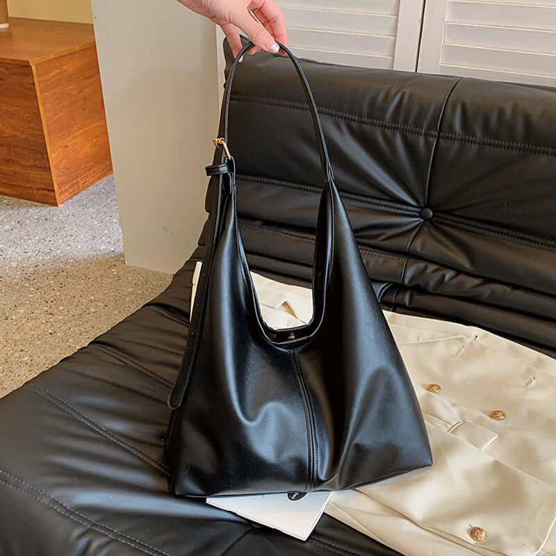 Large capacity commuter tote women's black bag on black couch.