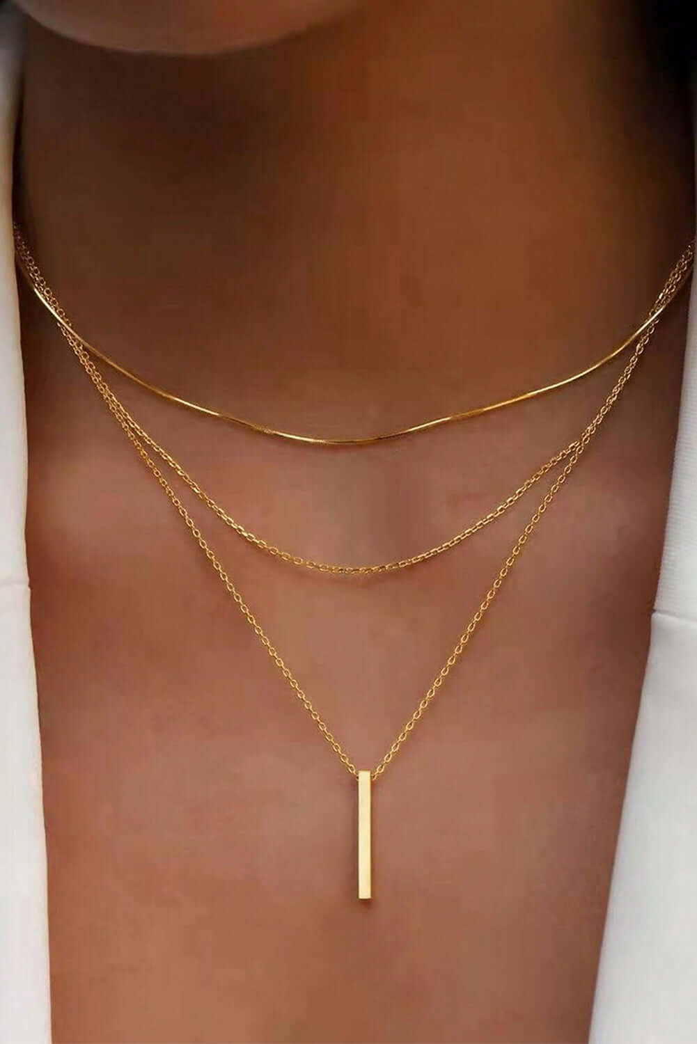 Elegant gold layered adjustable chain necklace featuring a chic gold bar pendant, perfect for versatile styling.