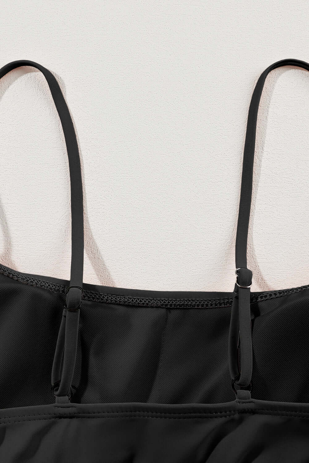 Close-up of black bikini with spaghetti straps, showcasing the adjustable design and smooth fabric.