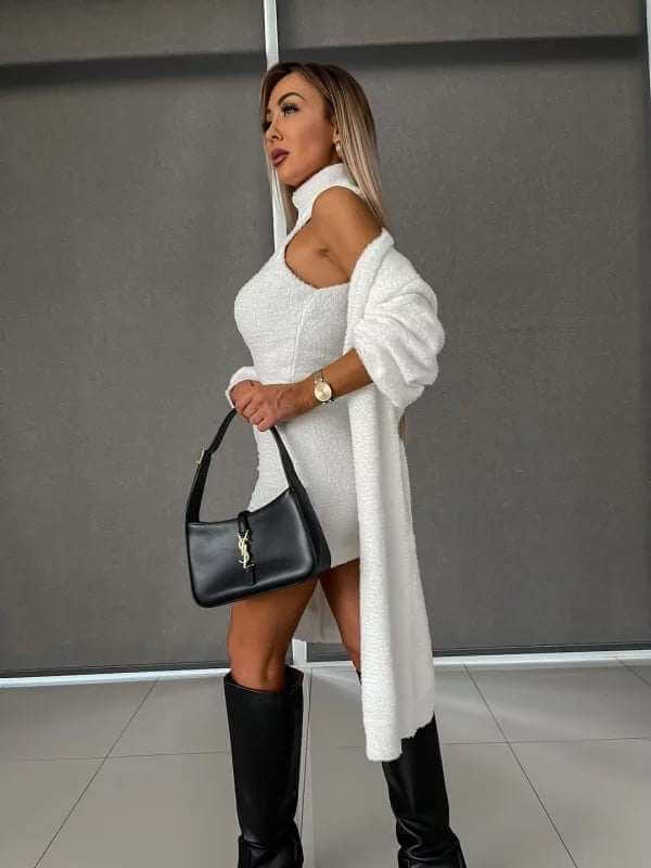 Woman wearing a white fleece-lined dress and coat, holding a black handbag.